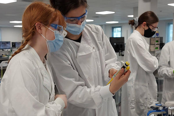 Two students in lab coats running experiments