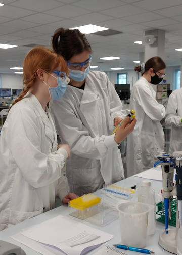 Two students in lab coats running experiments